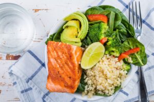 Saumon, avocat, légumes et riz sur assiette blanche.