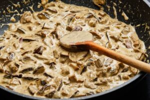 Poêlée de champignons crémeuse avec cuillère bois.
