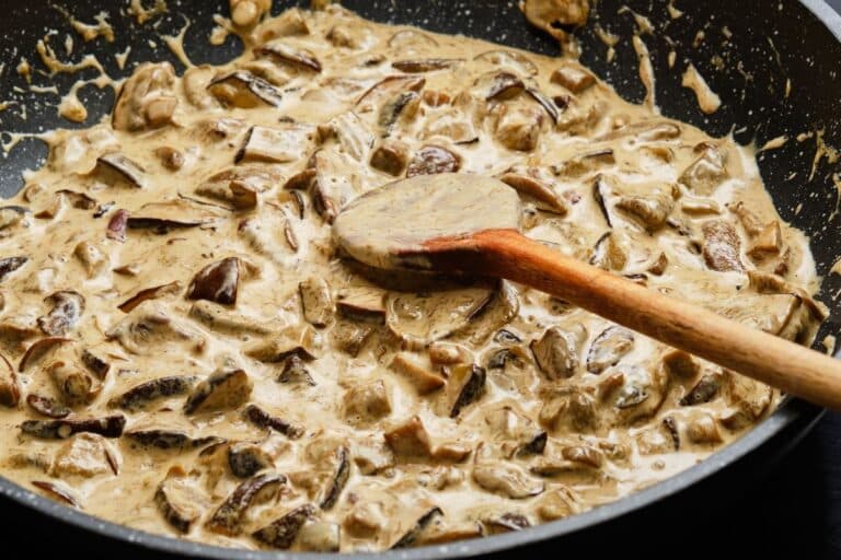 Poêlée de champignons crémeuse avec cuillère bois.