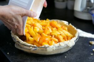 Préparation d'une tarte aux pêches maison.
