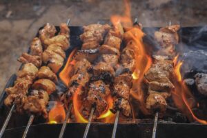 Brochettes de viande grillant sur barbecue enflammé.