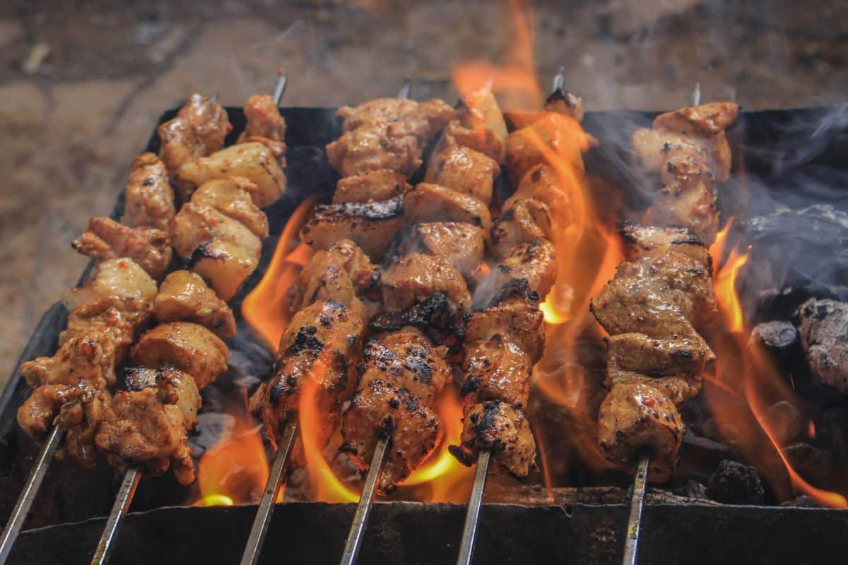 Brochettes de viande grillant sur barbecue enflammé.