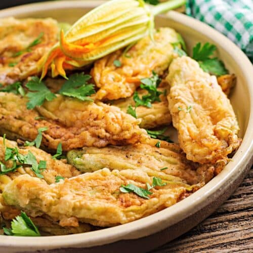 Fleurs de courgette farcies et frites dans une assiette.