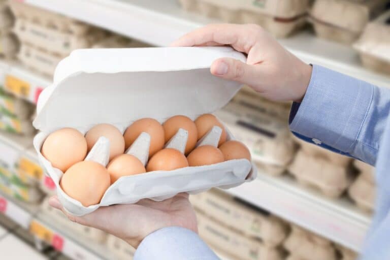 Carton d'œufs tenu en main au supermarché.