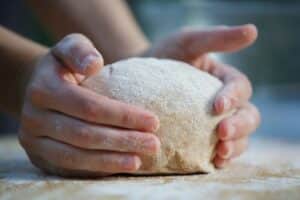 Mains pétrissant une pâte à pain.
