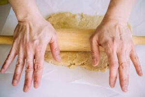 Main étale pâte avec rouleau à pâtisserie.