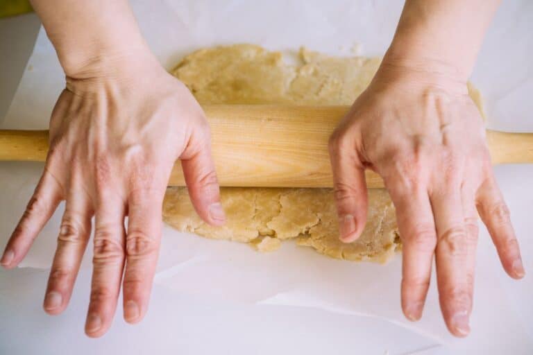Main étale pâte avec rouleau à pâtisserie.