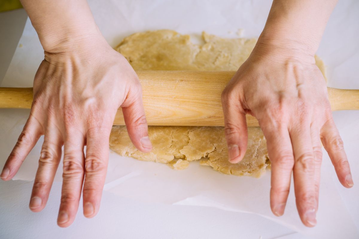 Main étale pâte avec rouleau à pâtisserie.