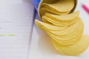 Chips sur table avec carnet et crayon rose.