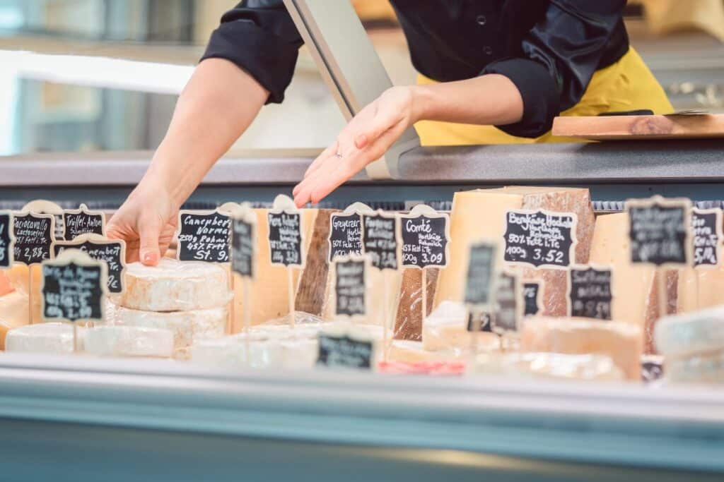 Fromager choisissant des fromages dans un étalage.