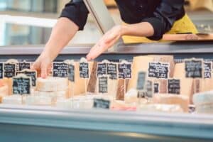 Fromager choisissant des fromages dans un étalage.