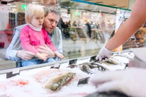 Enfant et adulte regardant des poissons au marché.