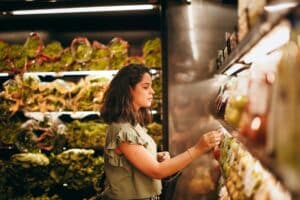 Femme choisit des légumes dans un supermarché.