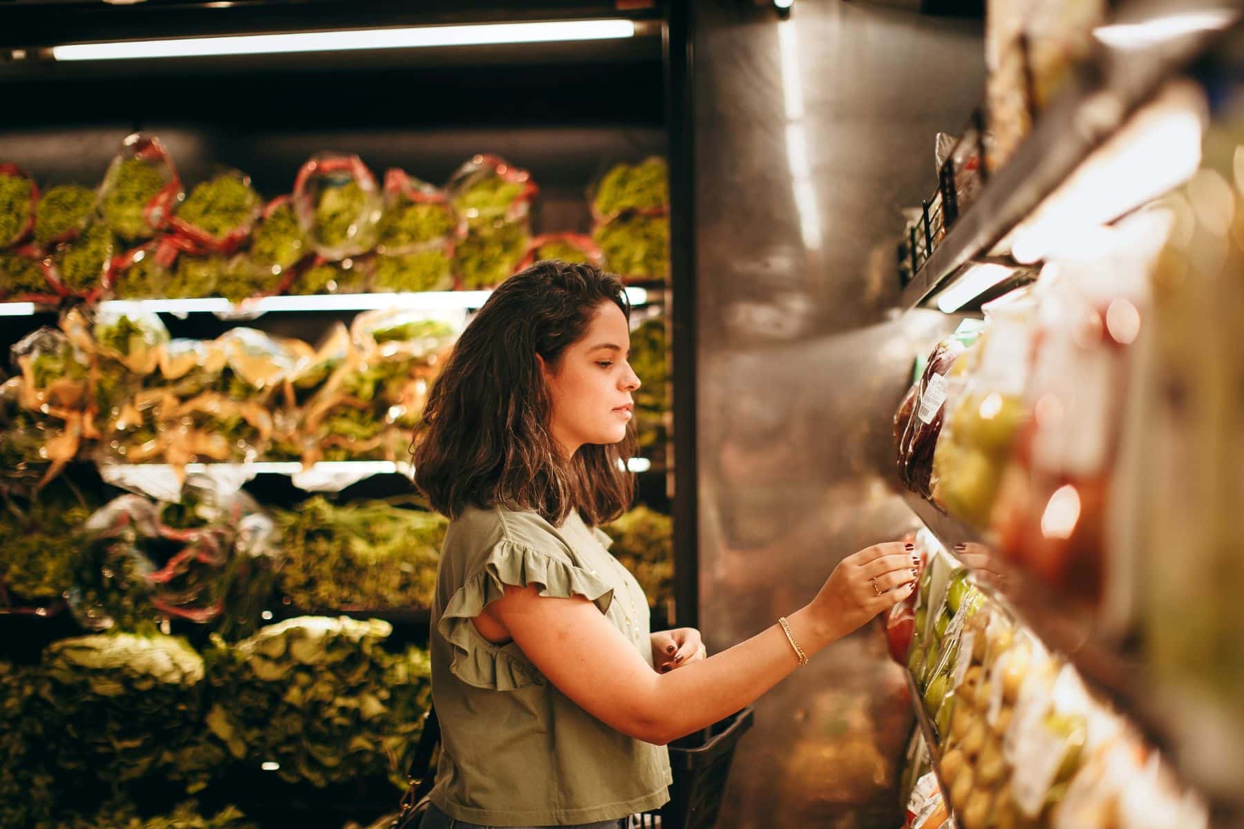 Femme choisit des légumes dans un supermarché.