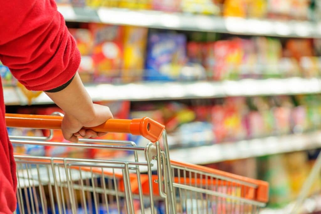 Personne poussant un chariot dans un supermarché coloré.