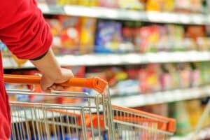 Personne poussant un chariot dans un supermarché coloré.