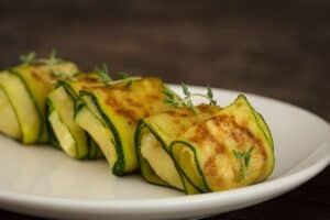 Roulés de courgettes grillées sur assiette blanche.