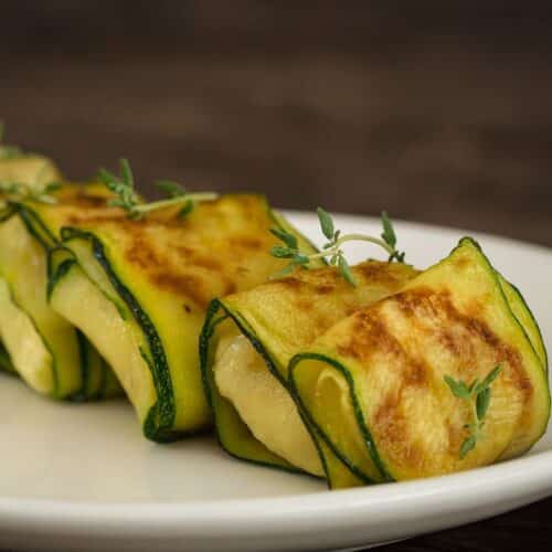 Roulés de courgettes grillées sur assiette blanche.