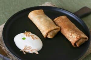Crêpes et crème sur assiette noire.
