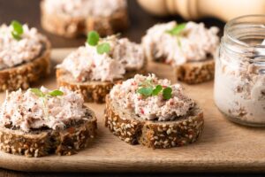 Tartines de rillettes sur une planche en bois.