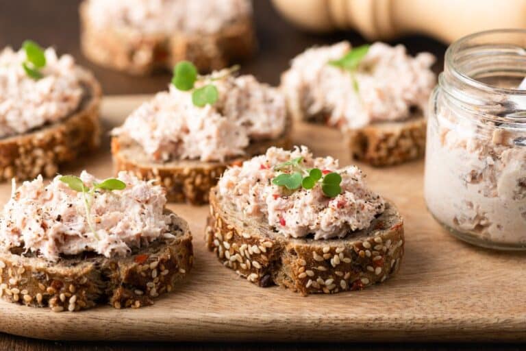 Tartines de rillettes sur une planche en bois.