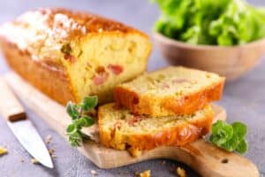 Cake salé tranché avec légumes, planche bois.