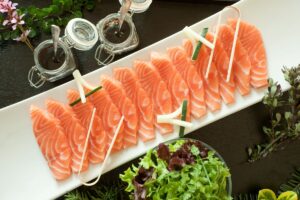 Sashimi de saumon avec sauce et verdure.