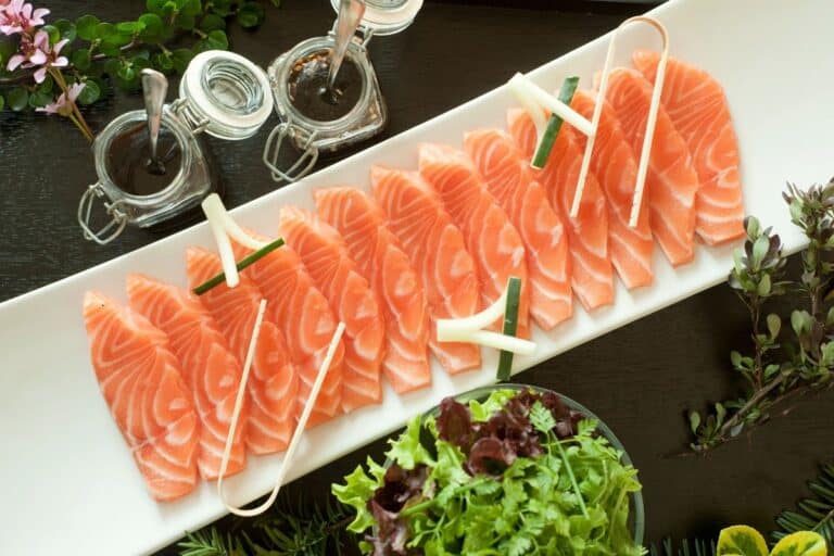 Sashimi de saumon avec sauce et verdure.