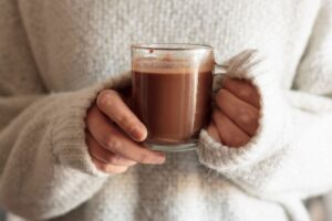 Mains tenant un chocolat chaud.