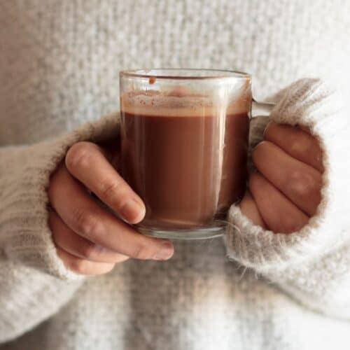 Mains tenant un chocolat chaud.