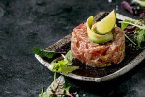 Tartare de thon avec avocat et citron sur assiette.