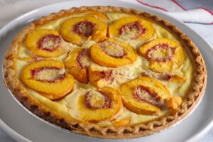 Tarte aux pêches sur assiette blanche.
