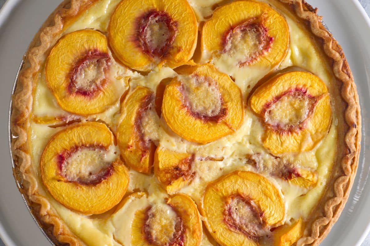 Tarte aux pêches sur assiette blanche.