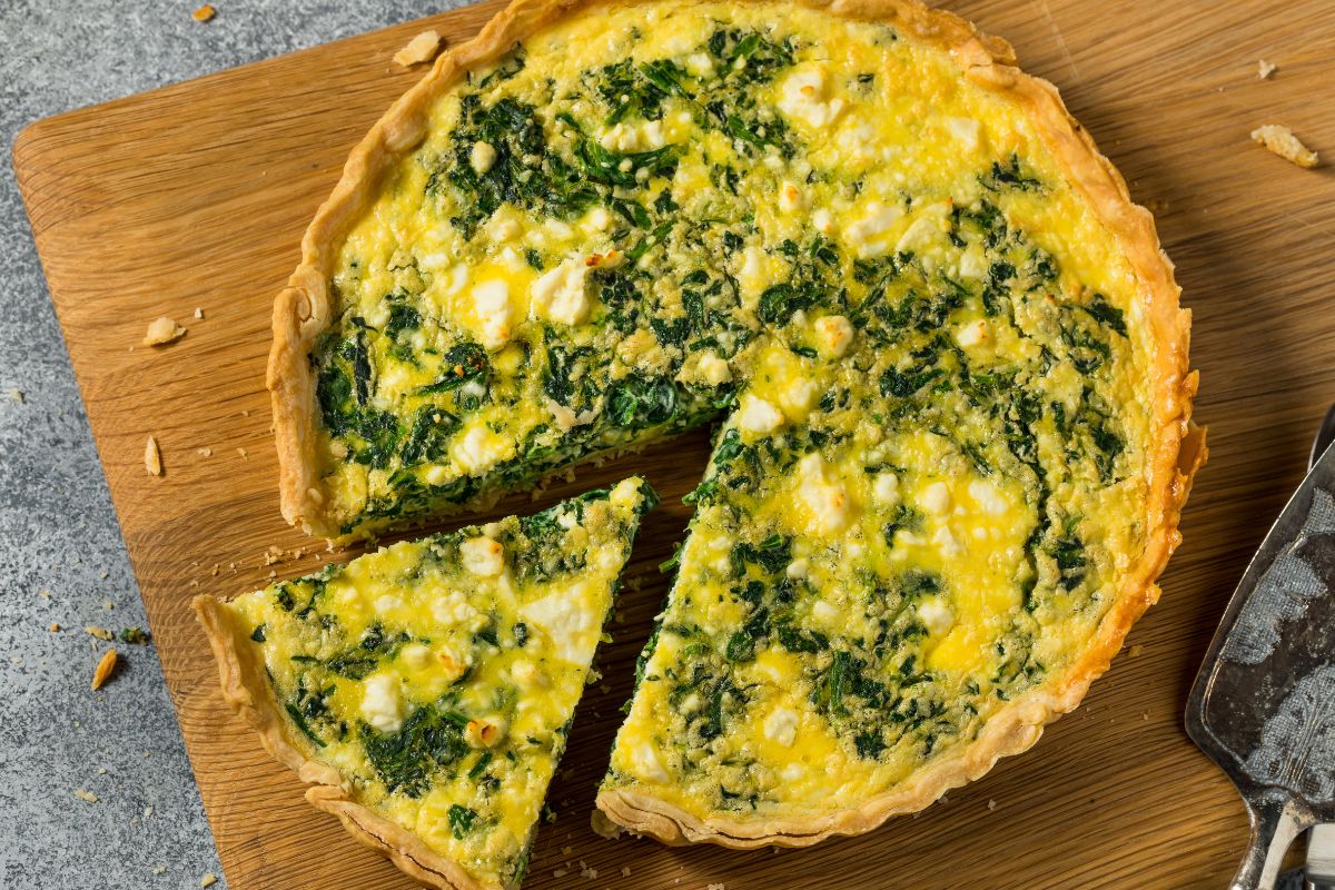 Quiche aux épinards et fromage sur planche en bois.