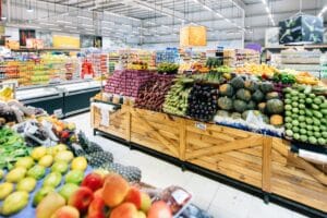 Supermarché avec fruits et légumes exposés.