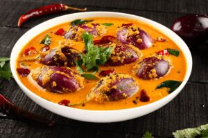 Curry d'aubergines violettes avec épices dans assiette blanche.