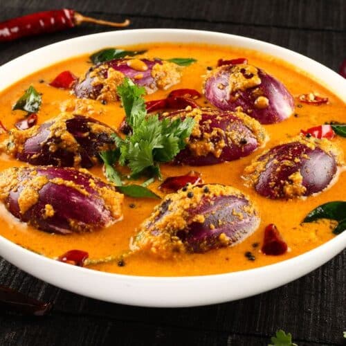 Curry d'aubergines violettes avec épices dans assiette blanche.