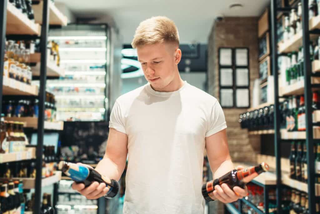 Homme choisissant des bouteilles au magasin.