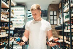 Homme choisissant des bouteilles au magasin.