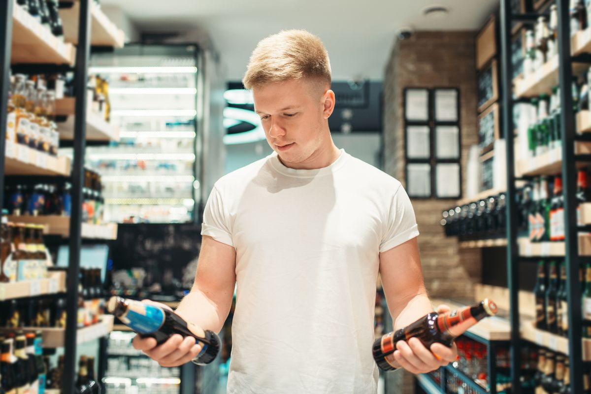 Homme choisissant des bouteilles au magasin.