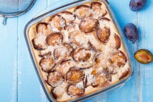 Clafoutis aux prunes sur table bleue.
