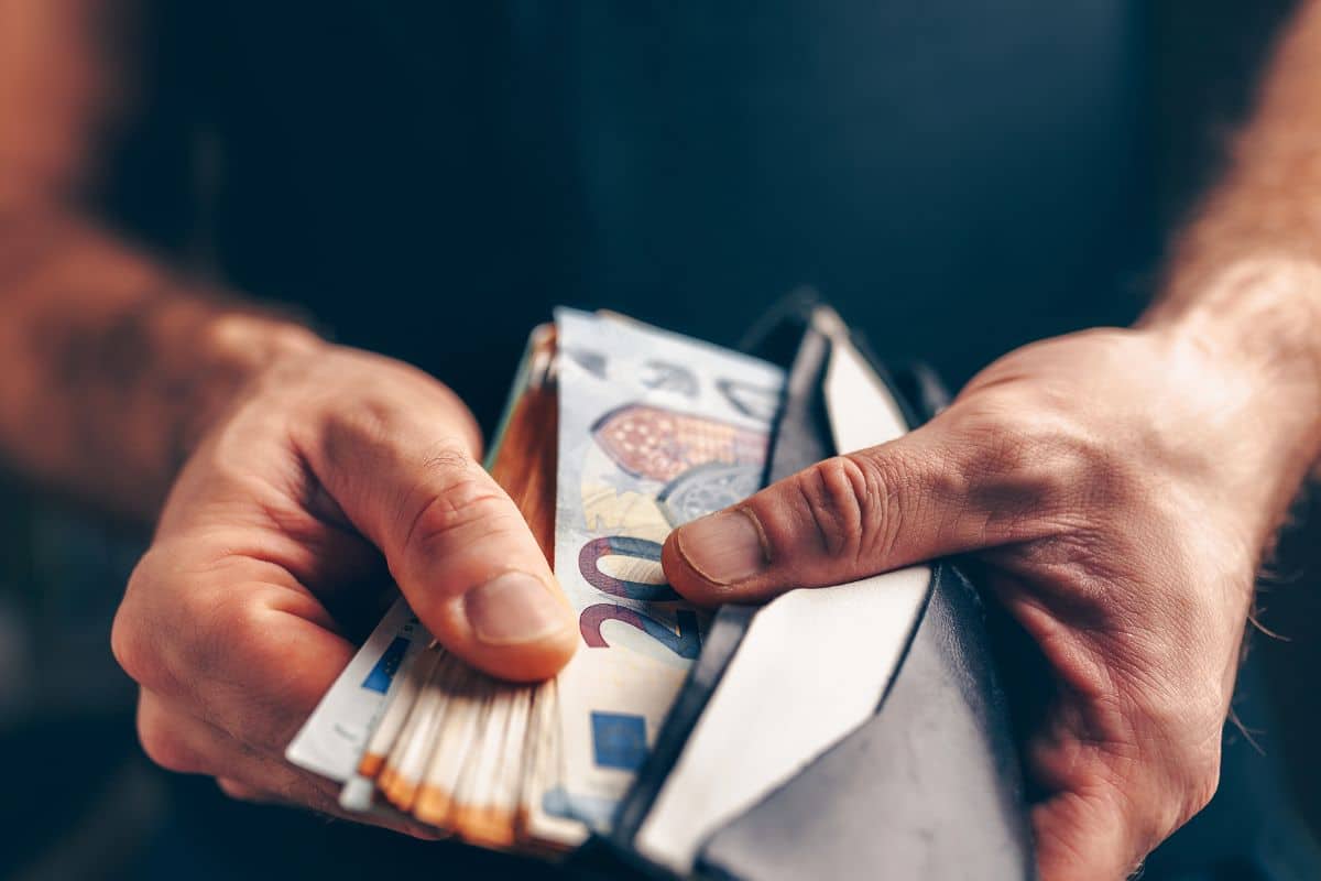 Homme tenant un portefeuille et des billets d'euros.