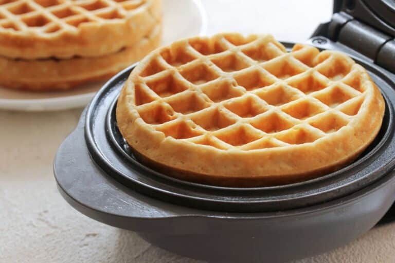 Gaufre dorée dans un gaufrier ouvert.