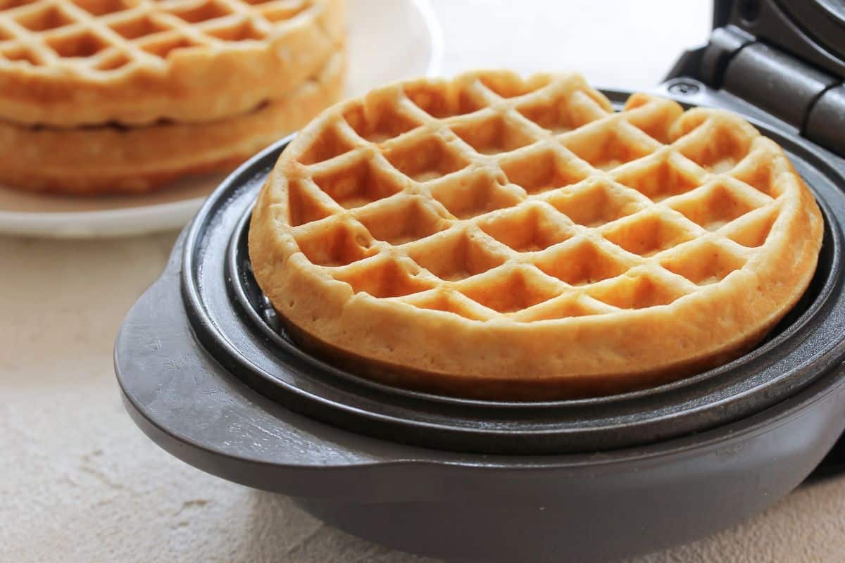 Gaufre dorée dans un gaufrier ouvert.
