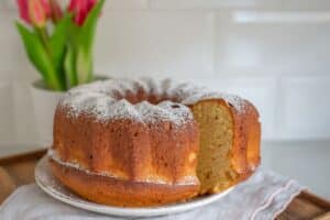 Gâteau Bundt saupoudré de sucre glace, tulipes en arrière-plan.