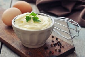 Mayonnaise dans un bol avec œufs et fouet.