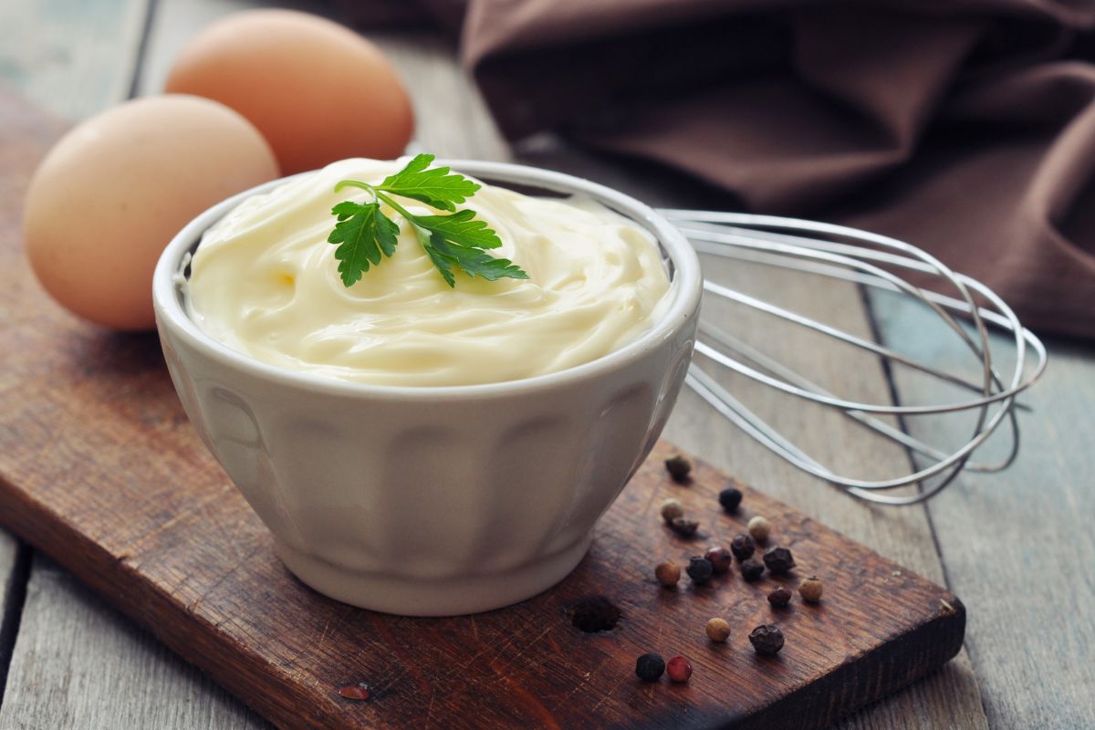 Mayonnaise dans un bol avec œufs et fouet.