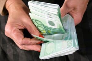 Mains comptant des billets de cent euros.