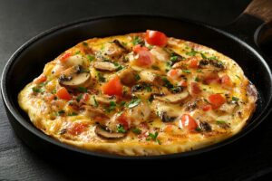 Omelette aux champignons et tomates dans une poêle.