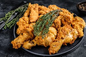 Poulet frit garni de thym sur assiette noire.